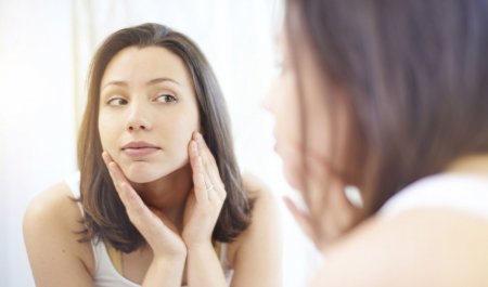 Woman checking her skin in a mirror