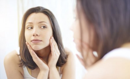 Woman checking her skin in a mirror